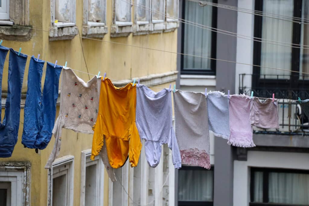 Traditional street scene with colorful clothes drying on a clothesline between weathered apartment facades in Istanbul, Turkey.