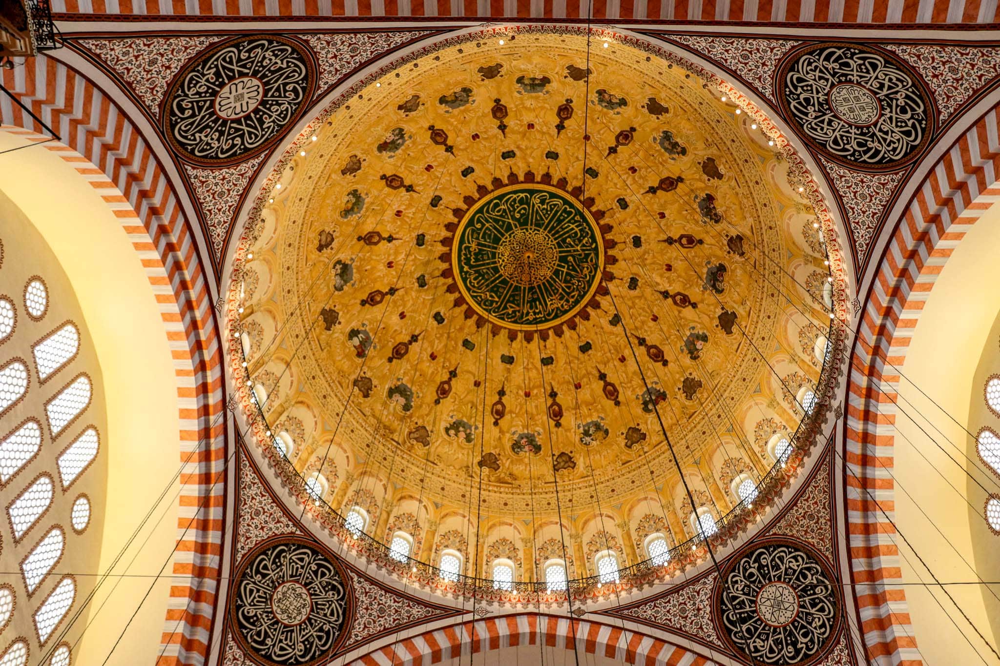The breathtaking interior of the Süleymaniye Mosque featuring an elaborately decorated golden dome with Islamic calligraphy and intricate tile work, Istanbul, Turkey.