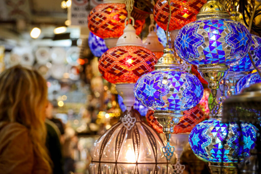 Vibrant handcrafted Turkish mosaic glass lamps in blue, purple and red hang on display in the Grand Bazaar of Istanbul, Turkey.