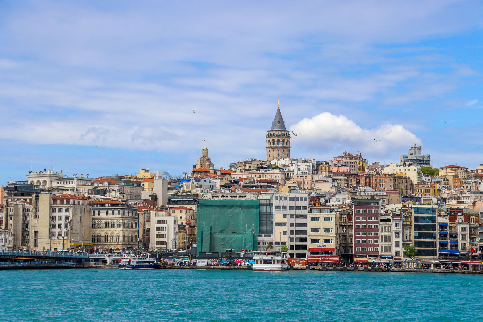 The medieval Galata Tower dominates the skyline above the colorful Karakoy waterfront district with the Golden Horn in the foreground, Istanbul, Turkey.