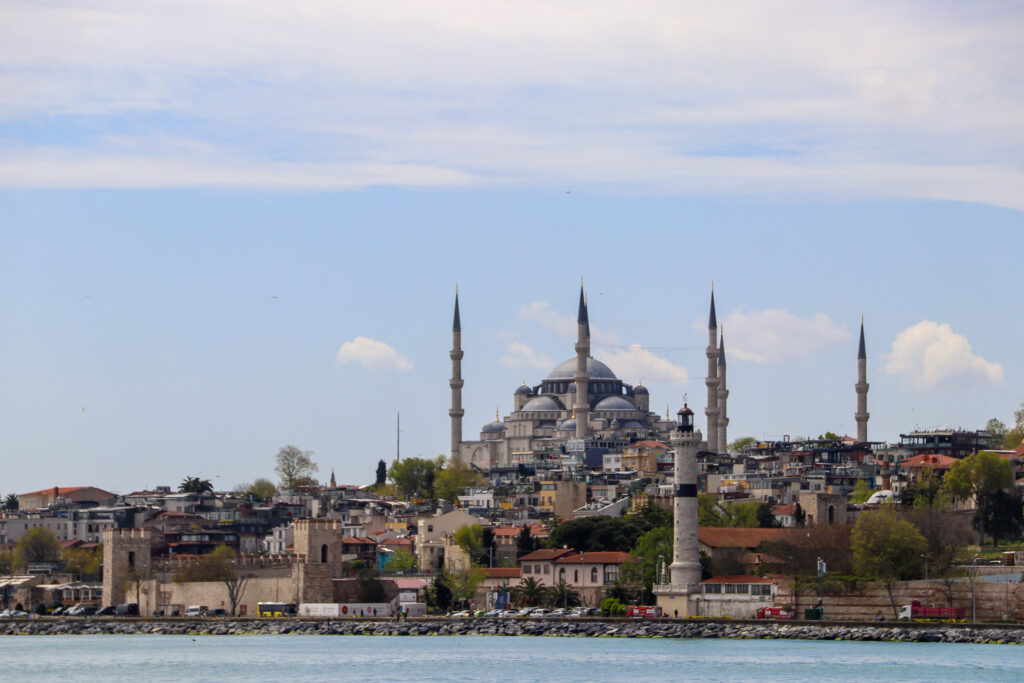 Wide-angle view of the Istanbul skyline dominated by mosque minarets in soft hazy overcast light, as seen from the water.