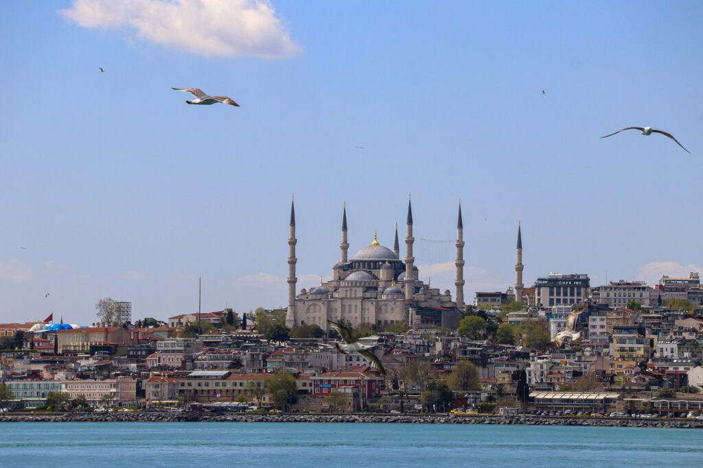 Broad panoramic view of the Istanbul skyline with multiple mosques and minarets seen from a Bosphorus ferry crossing, Turkey.