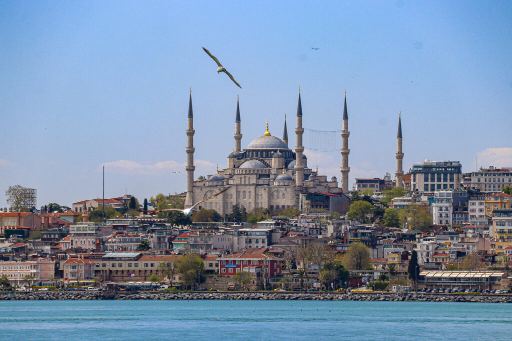 The iconic Istanbul mosque-dotted skyline rises above the calm blue waters of the Bosphorus as seen from a passing ferry, Turkey