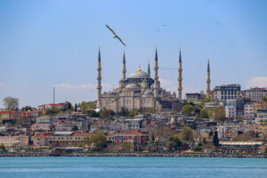 The iconic Istanbul mosque-dotted skyline rises above the calm blue waters of the Bosphorus as seen from a passing ferry, Turkey