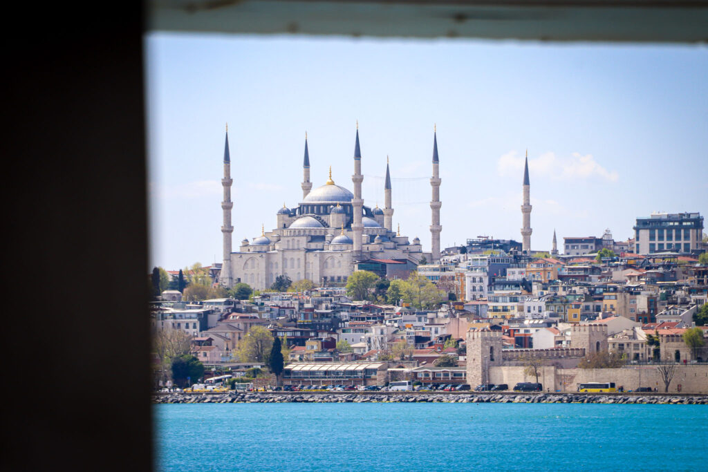 The iconic Blue Mosque (Sultan Ahmed Mosque) with its six minarets photographed through a dark window frame creating a dramatic contrast, Istanbul.