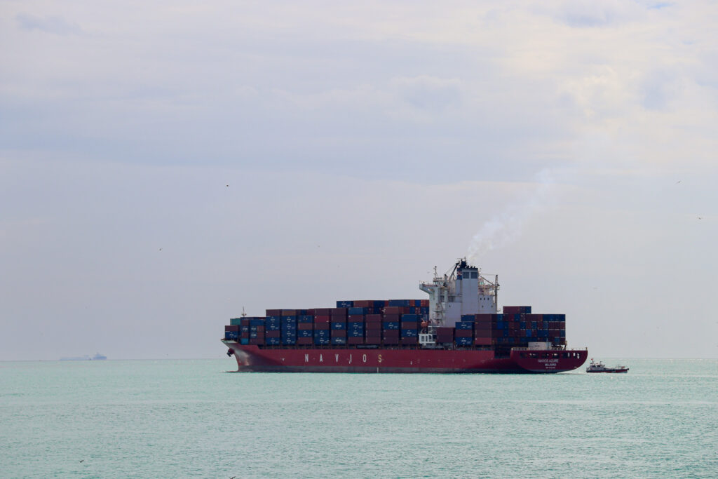 A large red container ship navigates the Bosphorus strait with the Istanbul skyline faintly visible in the background, Turkey.