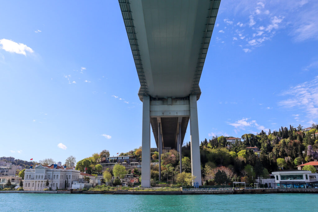 Wide-angle view from directly underneath the Bosphorus Bridge looking along the strait with the bridge's massive structure overhead, Istanbul, Turkey