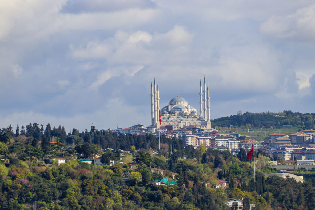 A wide view of the Istanbul skyline with mosque minarets rising above the city in a soft hazy atmosphere over the Bosphorus waters, Turkey.