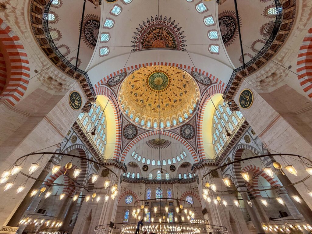 Blick zur kunstvoll gestalteten Kuppel einer historischen Moschee in Istanbul.
