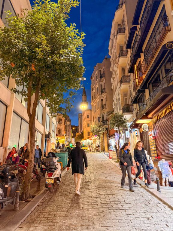 Belebte Straße in Beyoğlu am Abend mit Restaurants und Cafés.