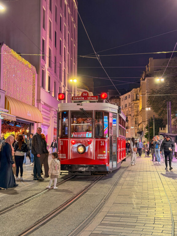 Rote nostalgische Straßenbahn auf der Istiklal Caddesi in Istanbul bei Nacht.